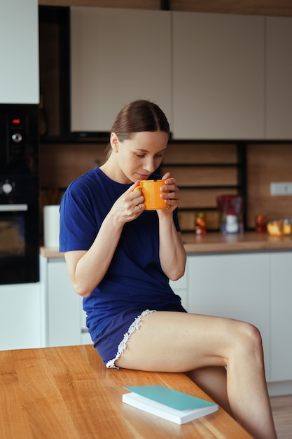 Foto gratuita mujer encantadora bebiendo una taza de té en la cocina