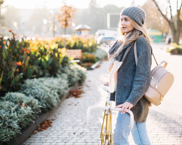 Mujer encantadora con bicicleta en el parque