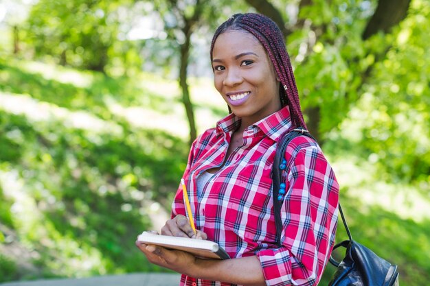 Mujer encantadora con el cuaderno en parque