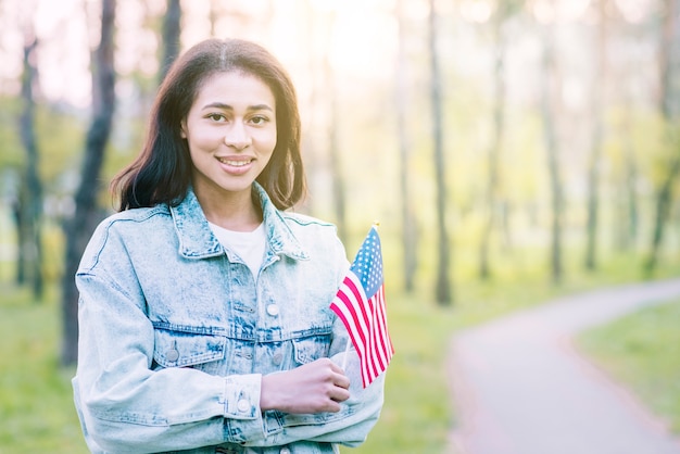 Mujer encantadora étnica con bandera bajo el sol