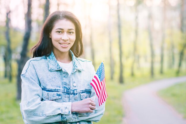 Mujer encantadora étnica con bandera bajo el sol