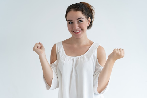 Foto gratuita mujer encantadora feliz bombeando puños y celebrando el éxito