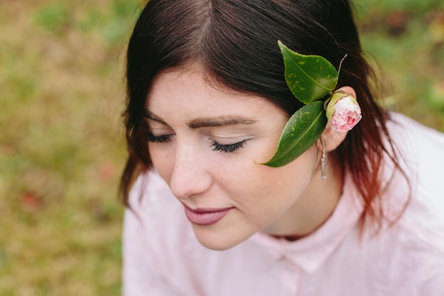 Mujer encantadora con flores y hojas en el pelo.