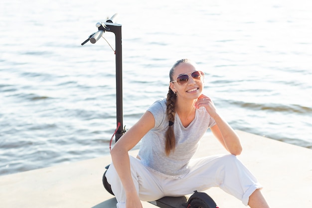 Foto gratuita mujer encantadora con gafas de sol posando en scooter