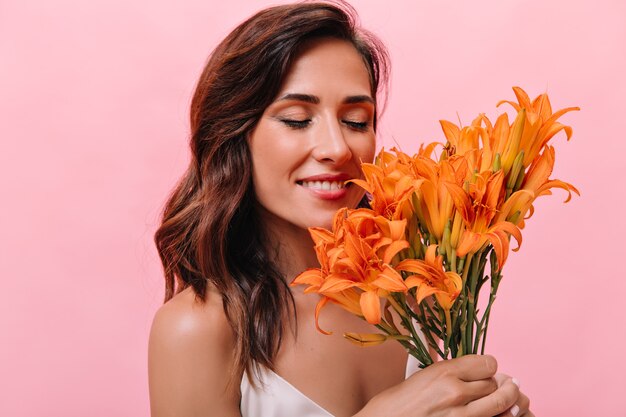 Mujer encantadora inhala aroma agradable de flores y sonrisas