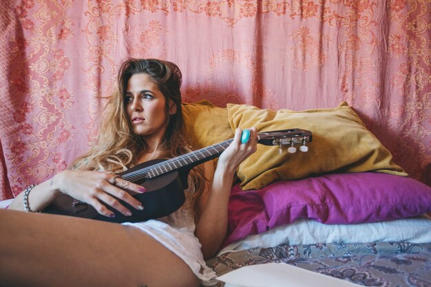 Mujer encantadora jugando ukulele negro