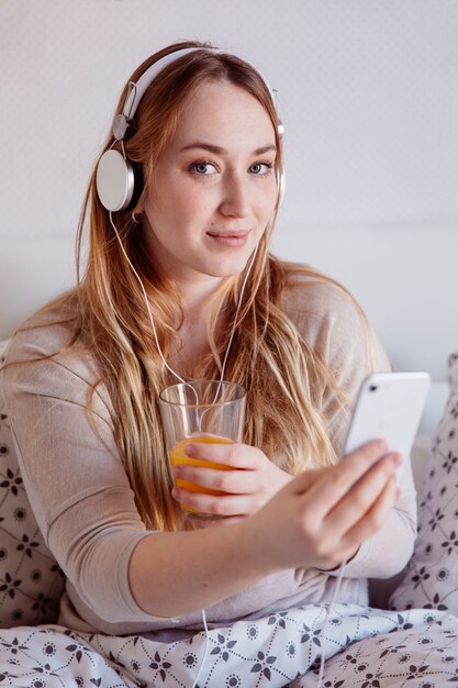 Mujer encantadora con jugo y teléfono inteligente