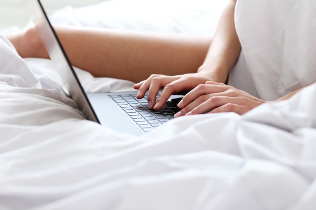 Mujer encantadora con laptop en la cama