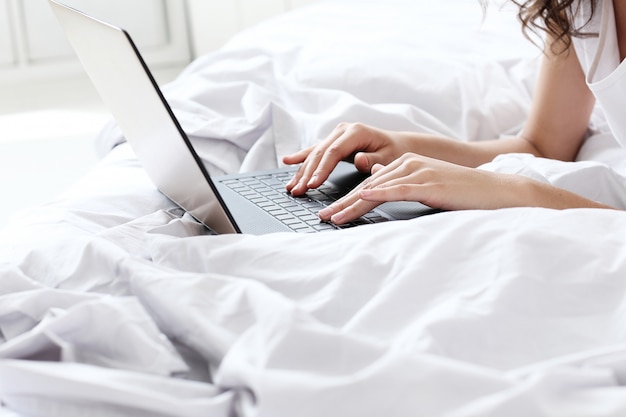 Foto gratuita mujer encantadora con laptop en la cama