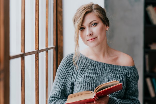 Mujer encantadora con libro mirando a cámara