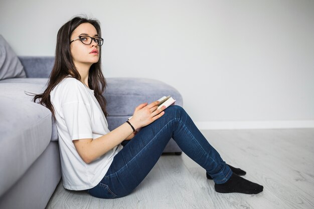 Mujer encantadora con libro mirando a otro lado