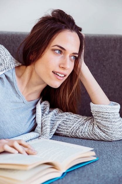 Mujer encantadora con libro en el sofá