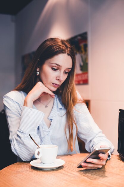 Mujer encantadora, navegación, teléfono inteligente, en, café