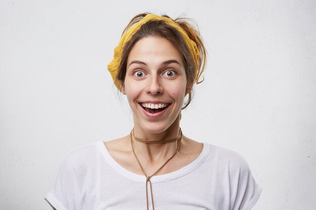 Mujer encantadora con ojos oscuros y piel pura que mira con gran expectación, con mirada emocionada, regocijándose de su éxito sin creer en sus ojos. Alegre mujer linda joven alegre en ropa casual