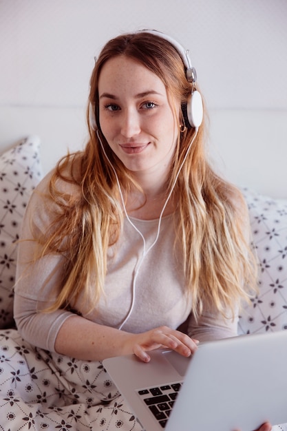 Foto gratuita mujer encantadora con ordenador portátil y auriculares