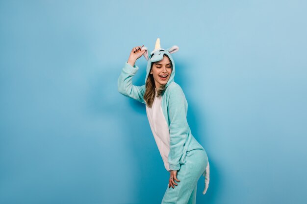 Mujer encantadora posando juguetonamente en traje de unicornio