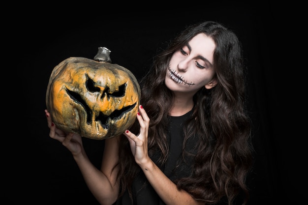 Mujer encantadora que muestra la calabaza de Halloween