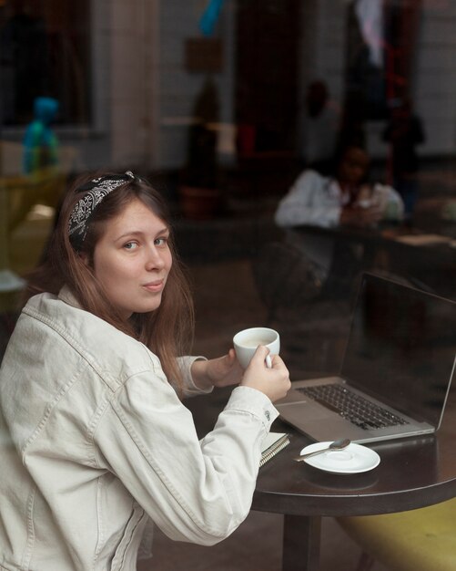 Mujer encantadora que sostiene la taza de café