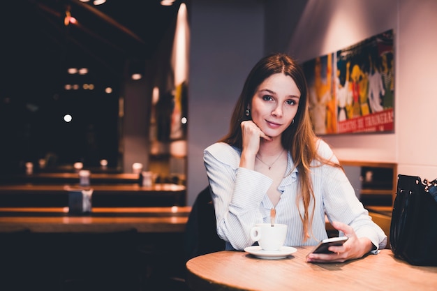 Mujer encantadora con smartphone mirando a cámara