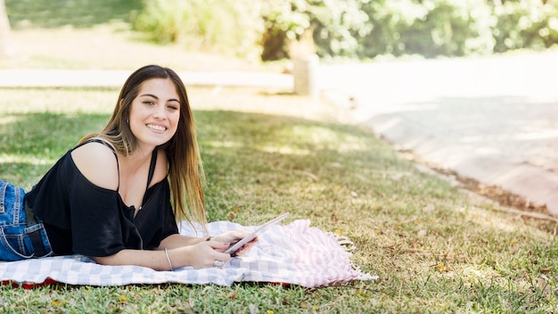 Foto gratuita mujer encantadora con tableta mirando a cámara