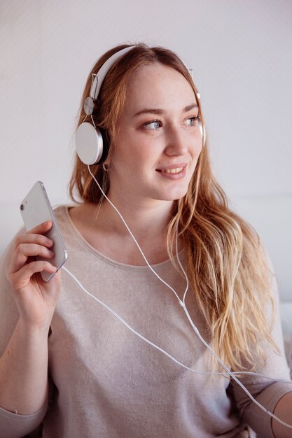 Mujer encantadora con teléfono inteligente y auriculares