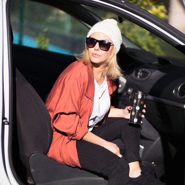 Mujer encantadora con termo en coche