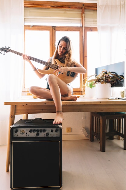 Foto gratuita mujer encantadora tocando la guitarra en la mesa