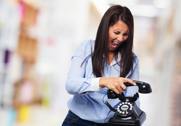 Mujer enfadada colgando un teléfono mientras grita