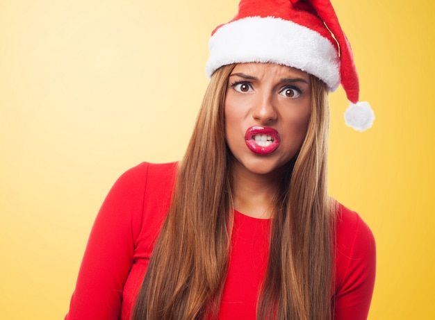 Mujer enfadada con el sombrero de papa noel en un fondo amarillo