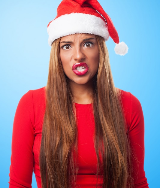 Mujer enfadada con el sombrero de papa noel en un fondo azul