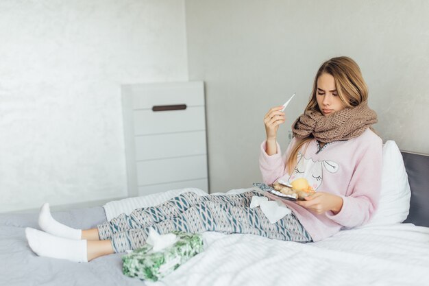 Mujer enferma acostada en la cama con fiebre alta y gripe