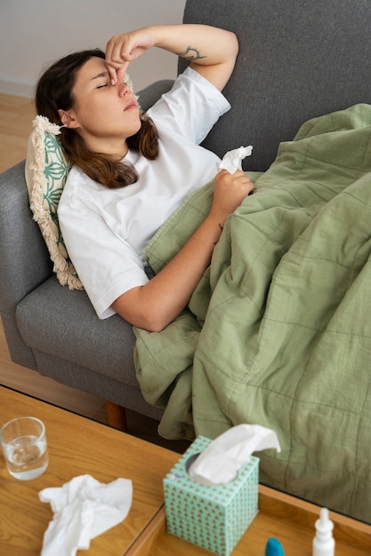 Foto gratuita mujer enferma de alto ángulo en el sofá en casa