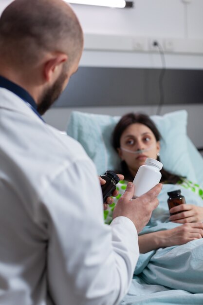 Mujer enferma descansando en la cama durante el examen médico con tubo de oygen nasal