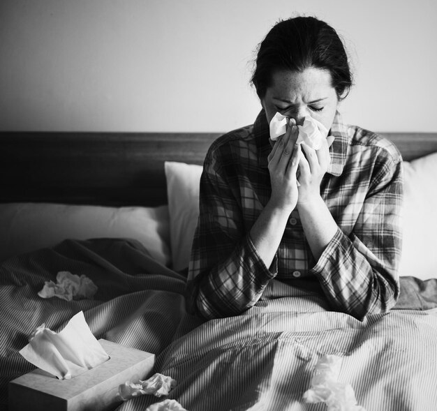 Una mujer enferma estornudando en la cama