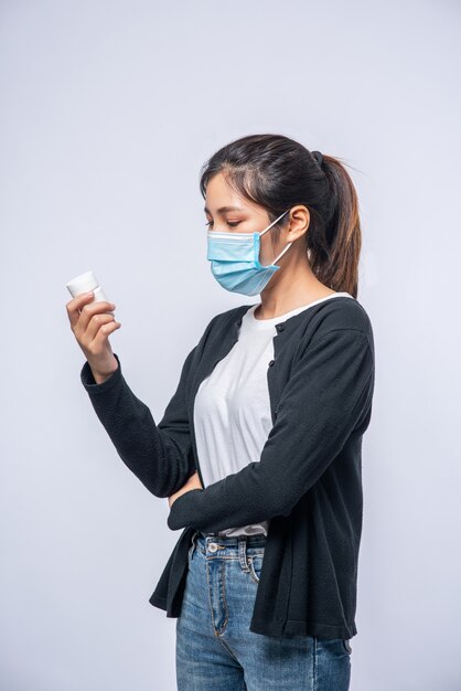 Una mujer enferma de pie con un frasco de medicina.