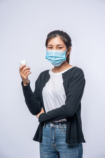 Una mujer enferma de pie con un frasco de medicina.