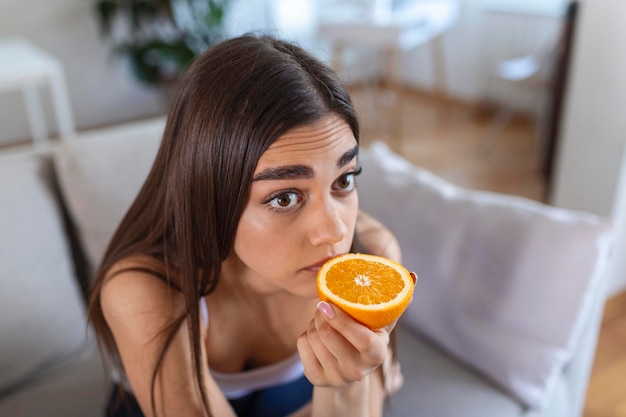 Mujer enferma que intenta sentir el olor de media naranja fresca tiene síntomas de infección por el virus de la corona Covid19 pérdida del olfato y el gusto Uno de los principales signos de la enfermedad