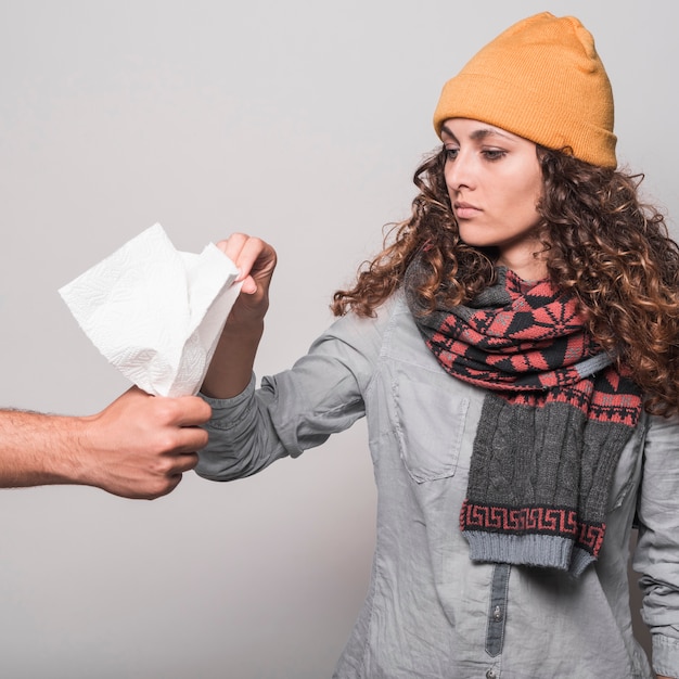 Mujer enferma tomando papel de seda de la mano del hombre contra el fondo gris