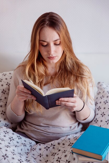 Mujer enfocada leyendo en la cama