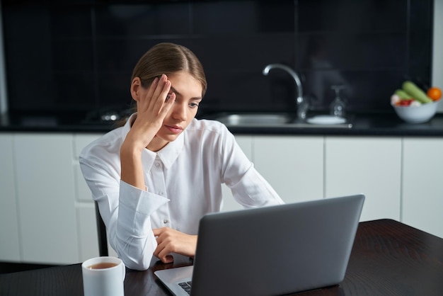 Mujer enfocada mirando la pantalla de la computadora en la mesa