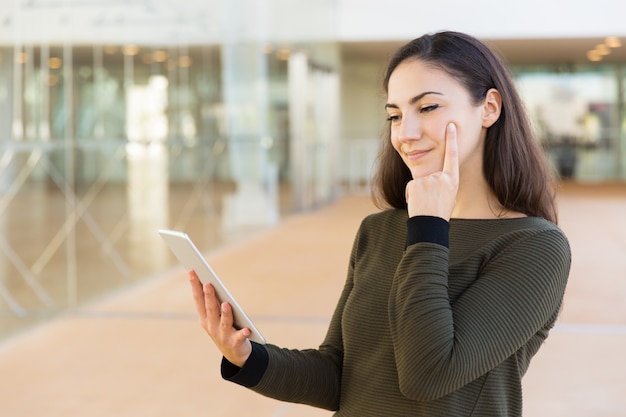 Mujer enfocada pensativa viendo contenido en tableta