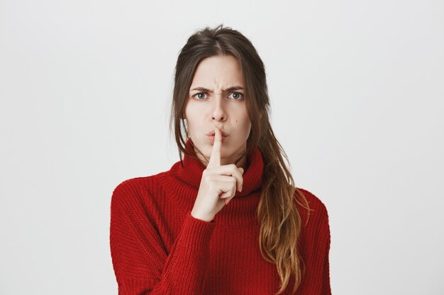 Mujer enojada callar con el dedo presionado a los labios