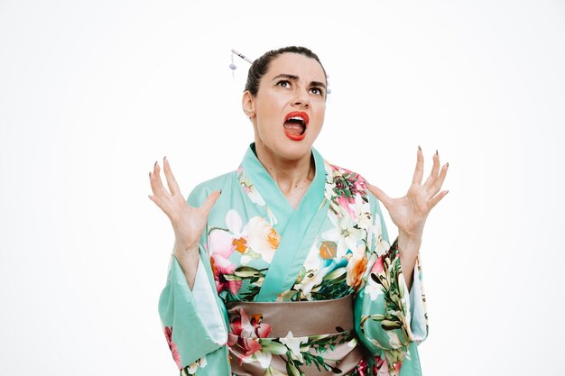 Mujer enojada en kimono japonés tradicional levantando las manos volviéndose loca gritando en blanco