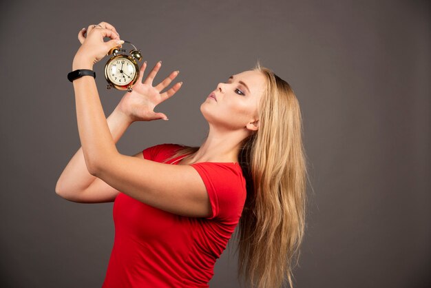 Mujer enojada quiere apagar el reloj en la pared negra.