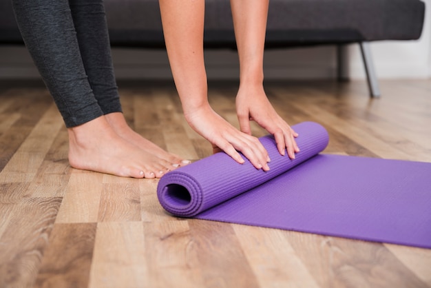 Mujer enrollando alfombra de yoga