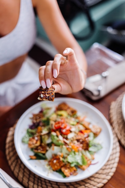 Foto gratuita mujer con ensalada de comida vegetariana vegana saludable colorida en la luz del día natural del café de verano