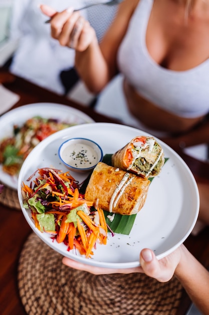 Foto gratuita mujer con ensalada de comida vegetariana vegana saludable colorida en la luz del día natural del café de verano