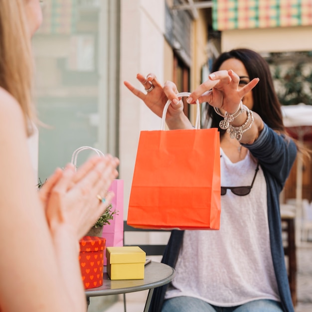 Mujer enseñando bolsa a amiga