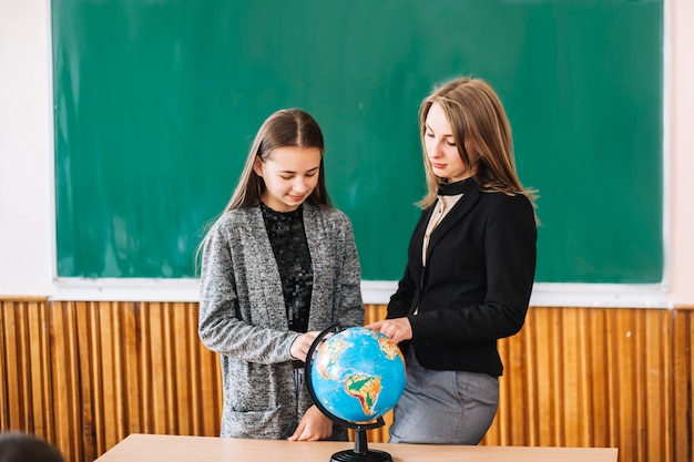 Mujer enseñando geografía a chica estudiante