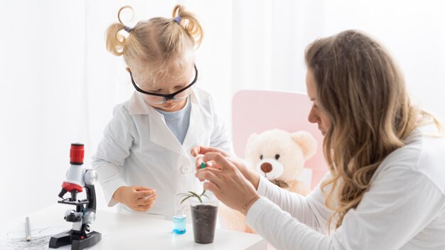 Mujer enseñando a un niño pequeño con gafas de seguridad sobre ciencia con microscopio